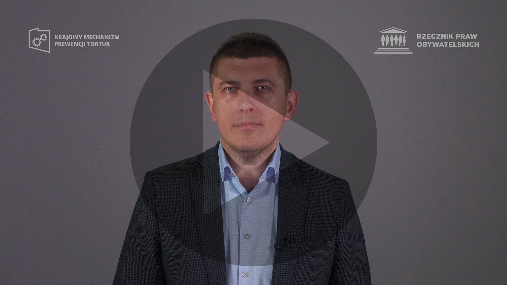 Kadr z nagrania przedstawiający ZRPO Wojciecha Brzozowskiego z naniesionym symbolem odtwarzania wideo - trójkątem w kole