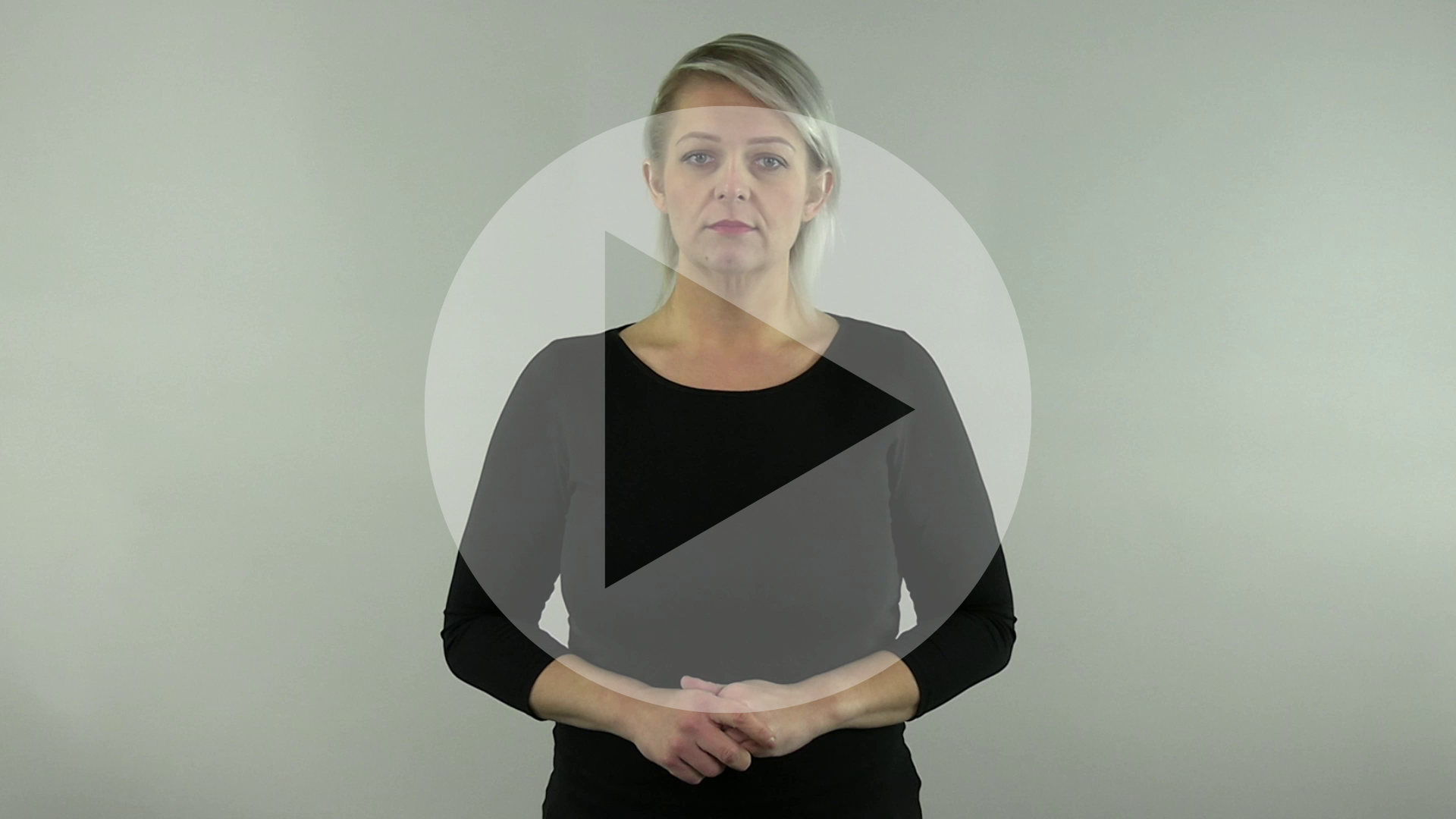 Kadr z nagrania przedstawiający tłumaczkę języka migowego z naniesionym symbolem odtwarzania wideo - trójkątem w kole