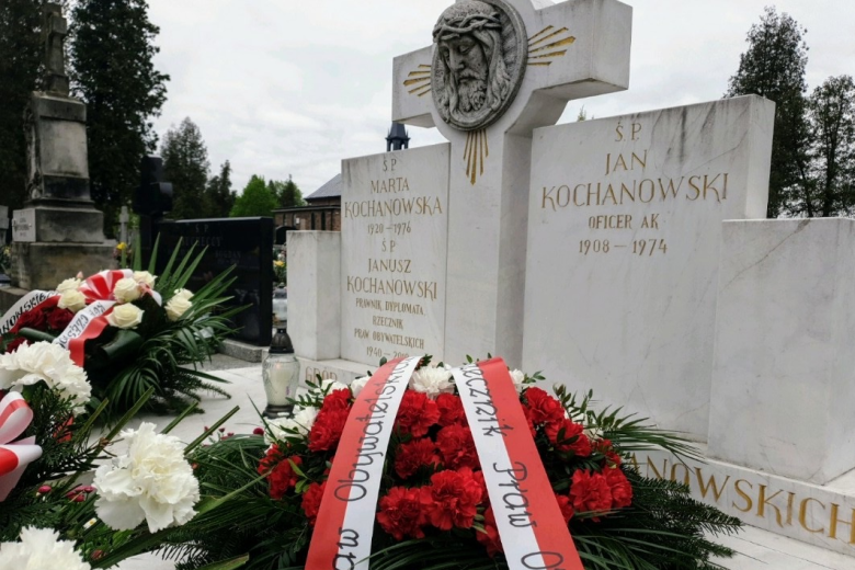 Biało-czerwone kwiaty i wieńce leżące na grobie