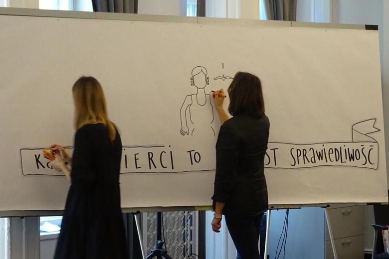 zdjęcie: przy ogromnej tablicy stoją dwie kobiety i rysują