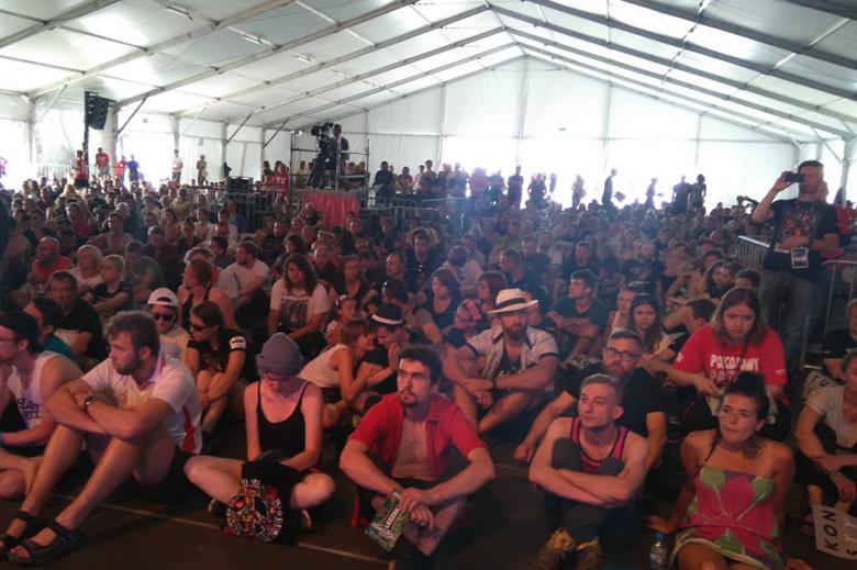 zdjęcie: w ogromnym namiocie na podłodze siedzi kilkadziesiąt osób