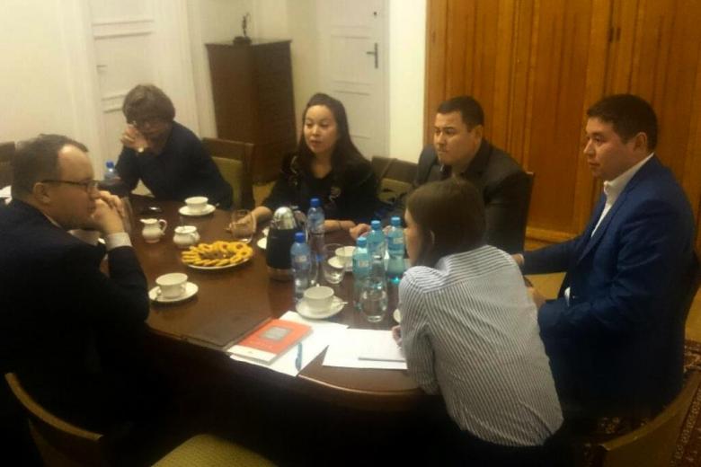 zdjęcie: kilka osób siedzi przy brązowym stole