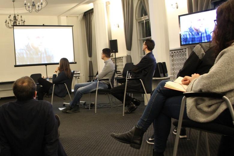 zdjęcie: kilka osób siedzi na sali i ogląda film wyświetlany przez projektor