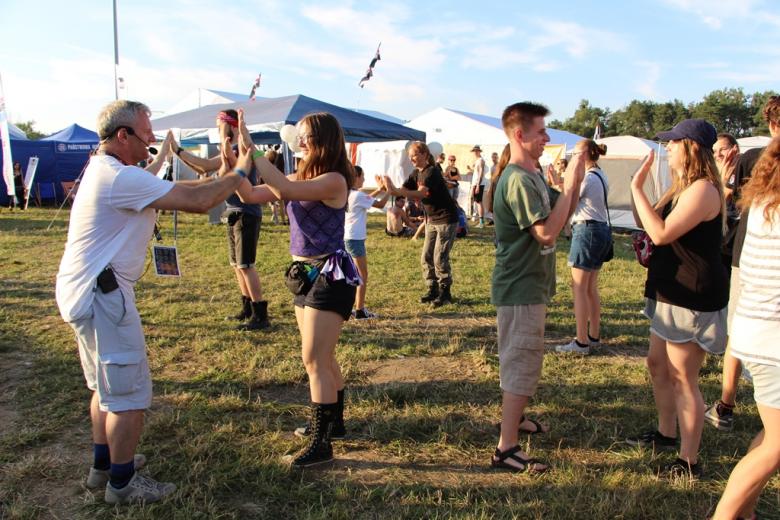 zdjęcie: kilkanaście osób tańczy na trawie
