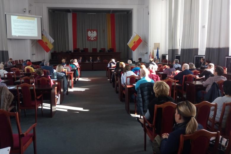 Ludzie na sali posiedzenia władz samorządowych, flaga Łodzi