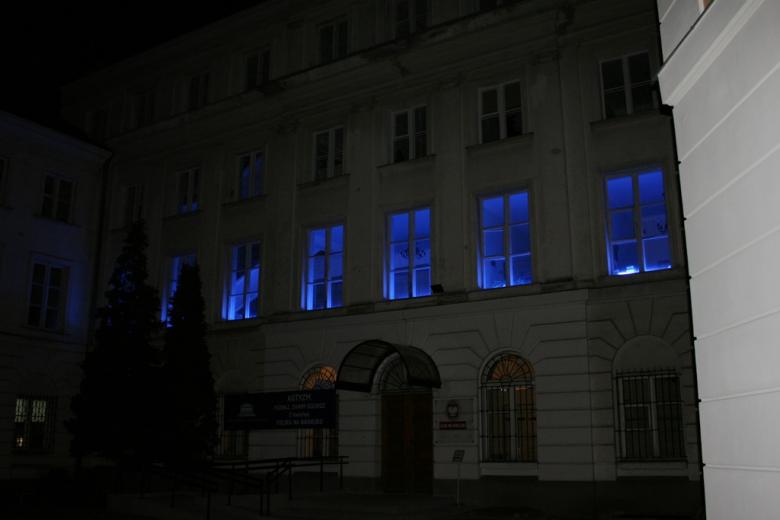 zdjęcie: nocą podświetlone na niebiesko okna w kamienicy na pierwszym piętrze