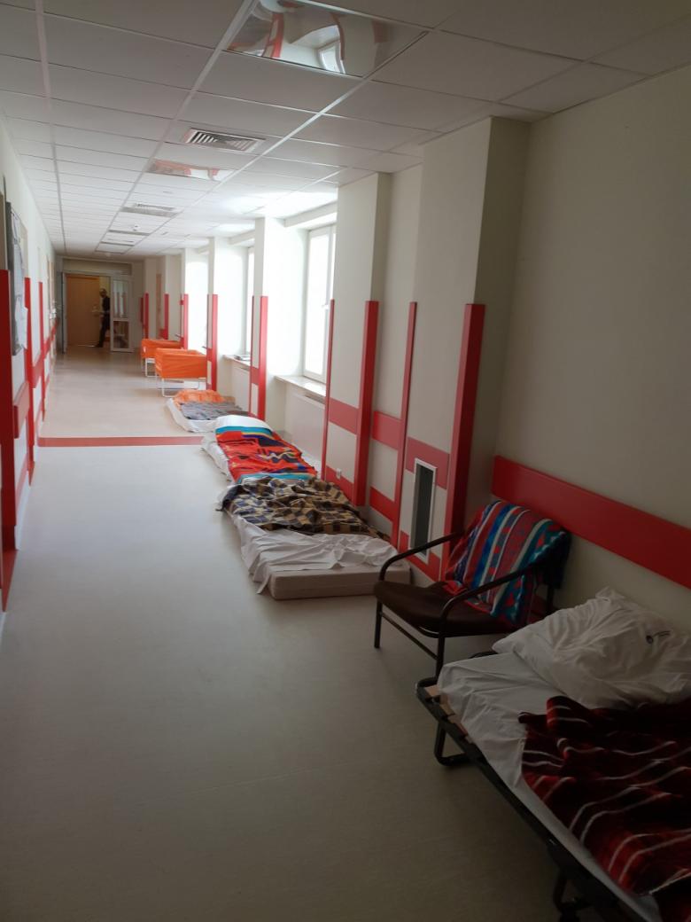 Łóżka i materace ułożone w szeregu na ładnie odnowionym szpitalnym korytarzu. Tu maja leżeć pacjenci
