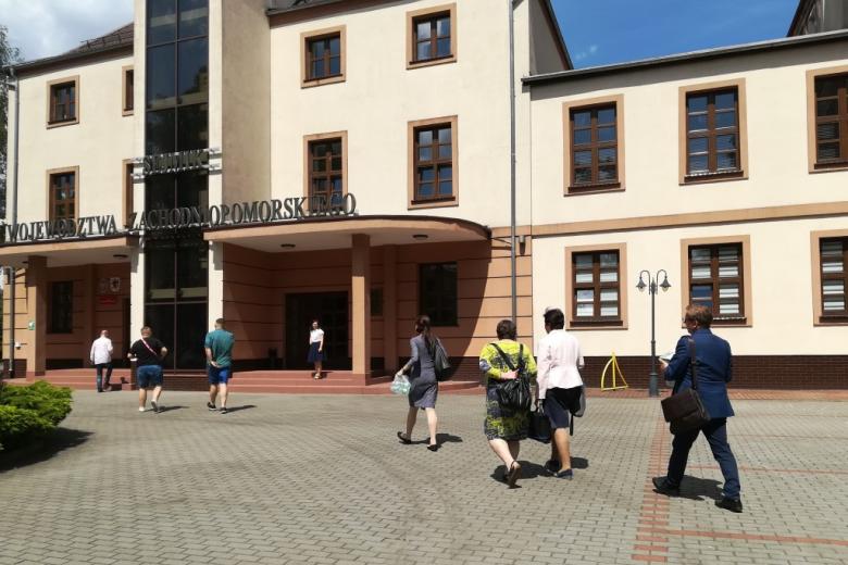 Ludzie wchodzą do budynku z naapisem Urząd Marszałkowski