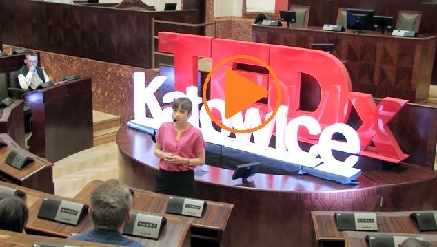 zdjęcie: kobieta w różowej bluzce przemawia na dużej sali, za nią napis TEDxKatowice