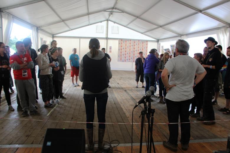 zdjęcie: ludzie stoją w namiocie w dwóch grupach, na pierwszym planie stelaże z mikrofonami