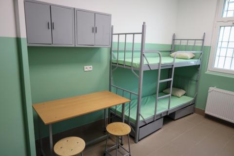 Łóżko piętrowe i stolik z dwoma krzesłami w celi więziennej 